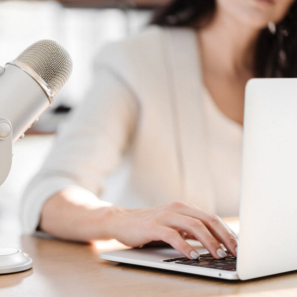Business Owner Fixing Broken Links On Wordpress Website At Desk Next To A Podcast Mic.