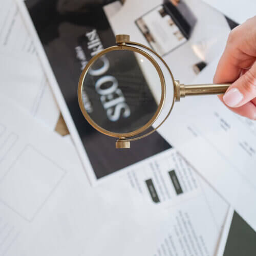 Image of Southern Creative owner, Stephanie O'Keefe, holding a magnifying glass over SEO strategy papers helping strategize how to get found online with seo.