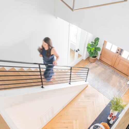 seo strategist and wordpress web designer, stephanie okeefe, walking up stairs in raleigh house holding laptop