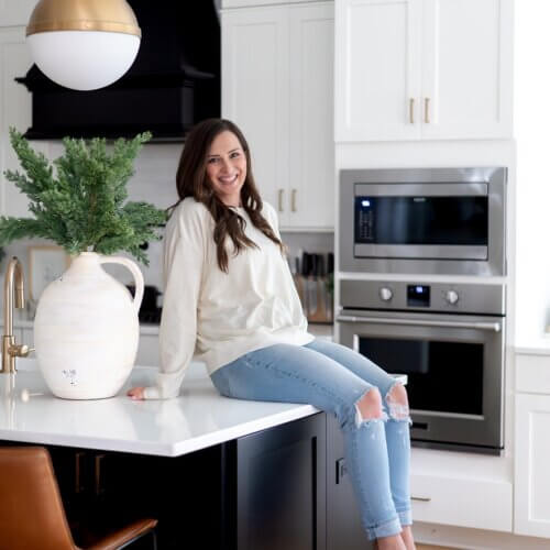 Stephanie Okeefe, Owner Of Southern Creative Sitting On Kitchen Counter.