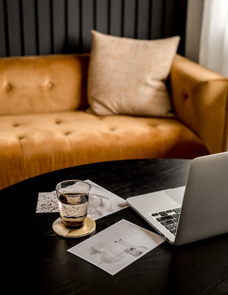 Image Of Brown Couch With Laptop Next To Papers During Meeting Discussing Search Generative Experience.