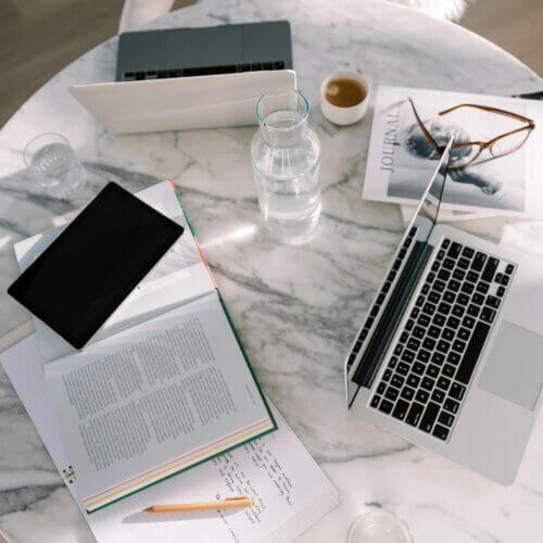 laptop on desk with papers and phone