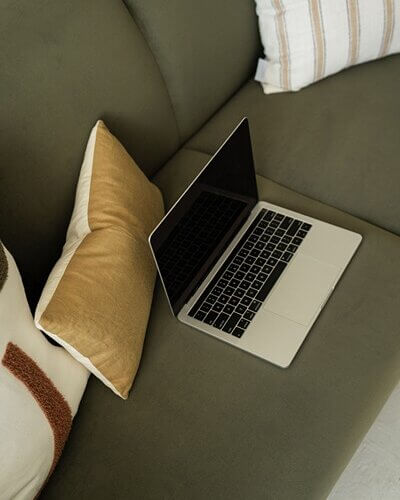 Laptop on couch, working on IDX on WordPress website