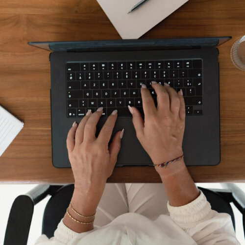 Overhead view of hands typing on a laptop next to a notebook while checking Google Search Console indexing