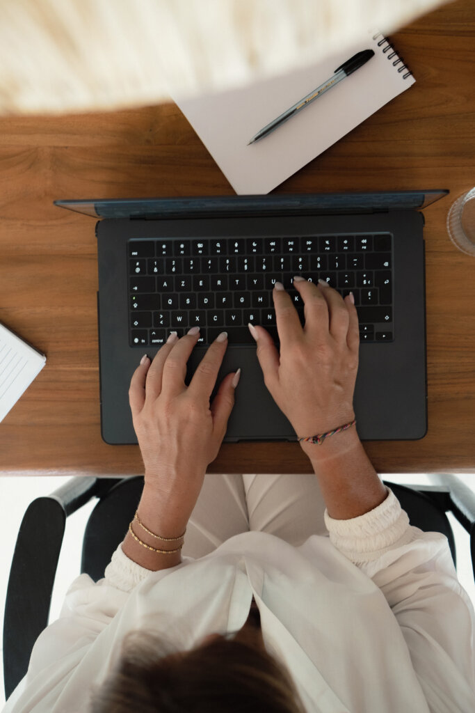 Crawled – Currently Not Indexed? Here’s What It Means (And What To Do) Overhead View Of Hands Typing On A Laptop Next To A Notebook While Checking Google Search Console Indexing