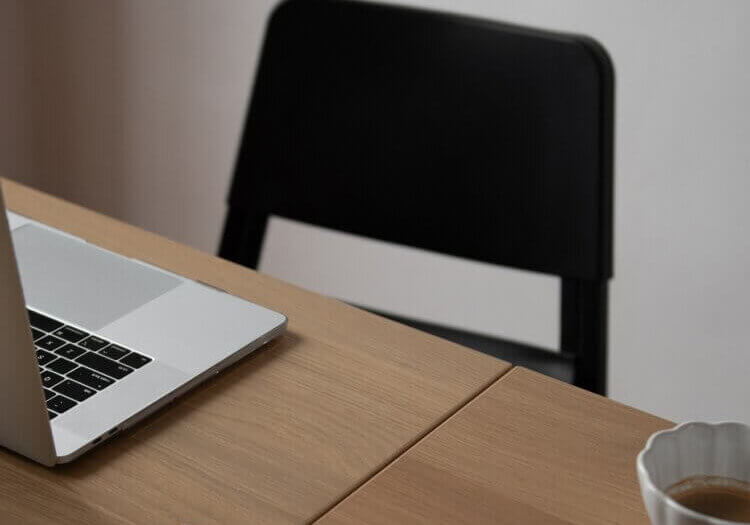 laptop on desk with book open at home office