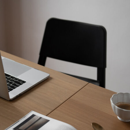 laptop on desk with book open at home office