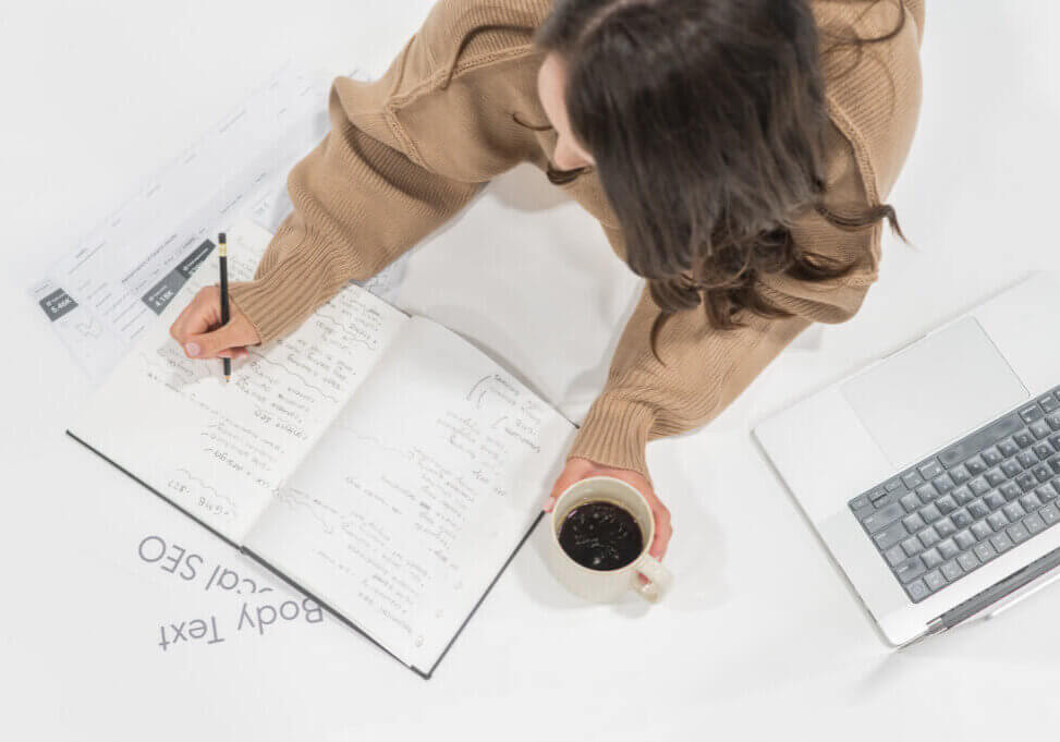 Stephanie O'Keefe writing out information comparing Beaver builder vs. elementor on notebook