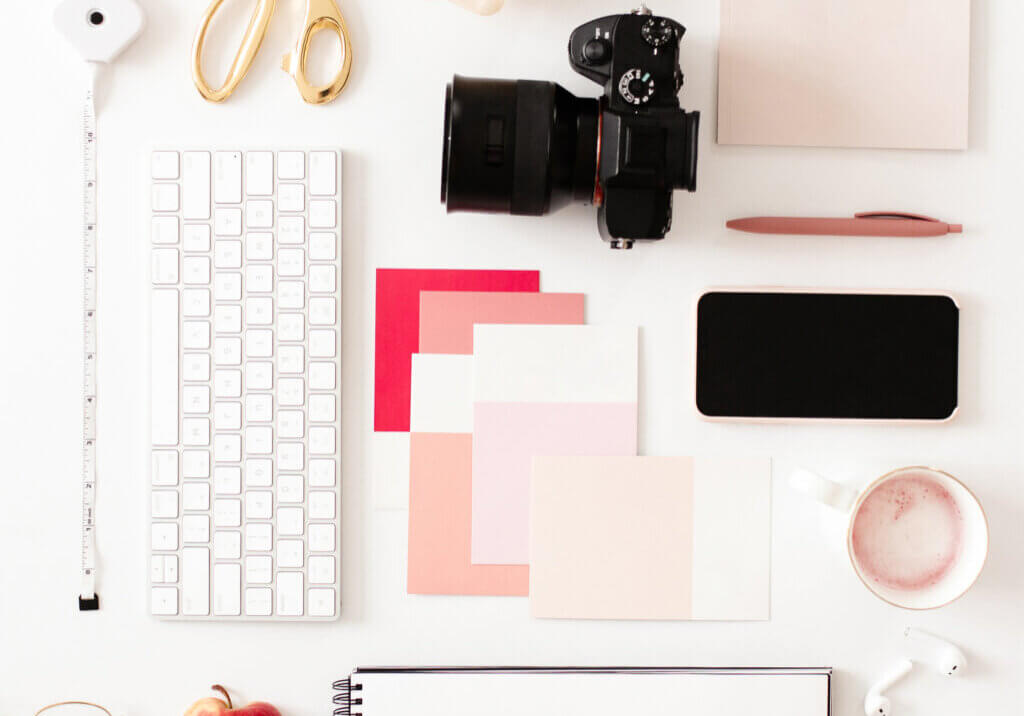 Flat lay of a camera, keyboard, phone and notebook on a desk for optimizing website images for SEO