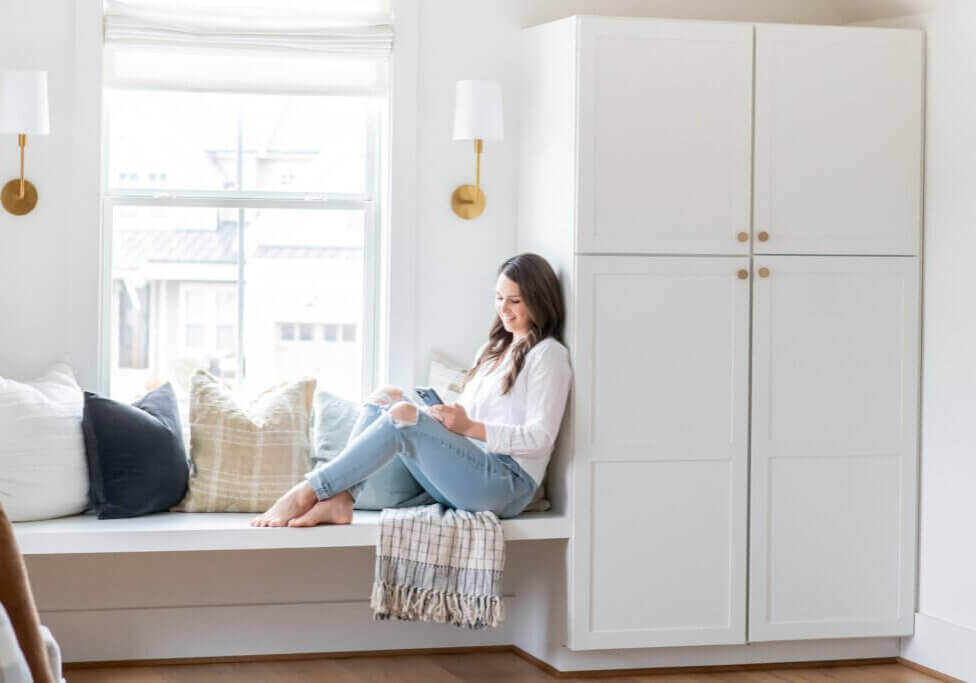 Southern Creative Owner, Steph O'Keefe working on Keyword Research for beginners on phone wearing a white shirt and blue jeans at home office in Raleigh, NC.