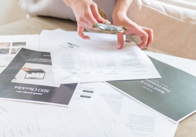 SEO strategist, Stephanie O'Keefe holding magnifying glass while looking through SEO papers