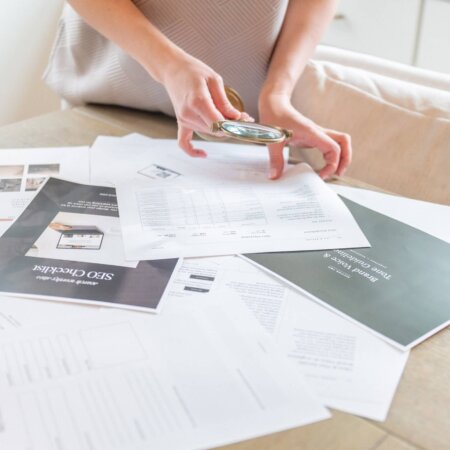 SEO strategist, Stephanie O'Keefe holding magnifying glass while looking through SEO papers