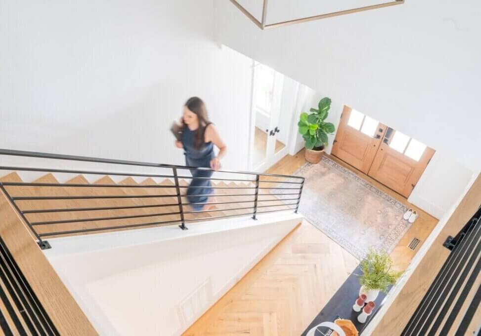 seo strategist and wordpress web designer, stephanie okeefe, walking up stairs in raleigh house holding laptop