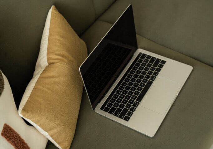 laptop on green couch with yellow pillow