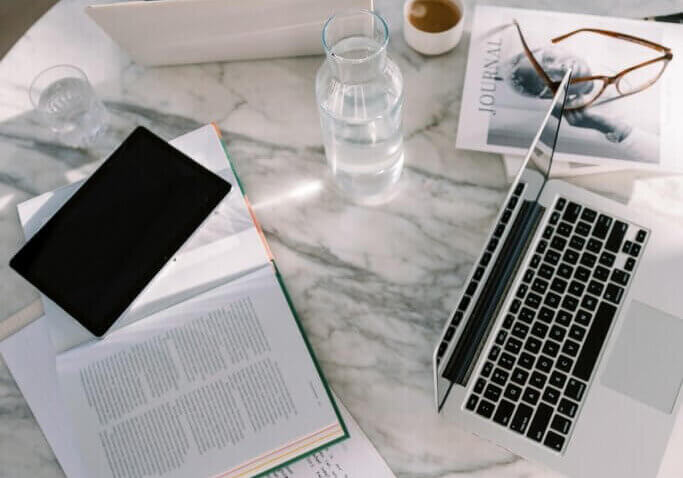 laptop on desk with papers and phone